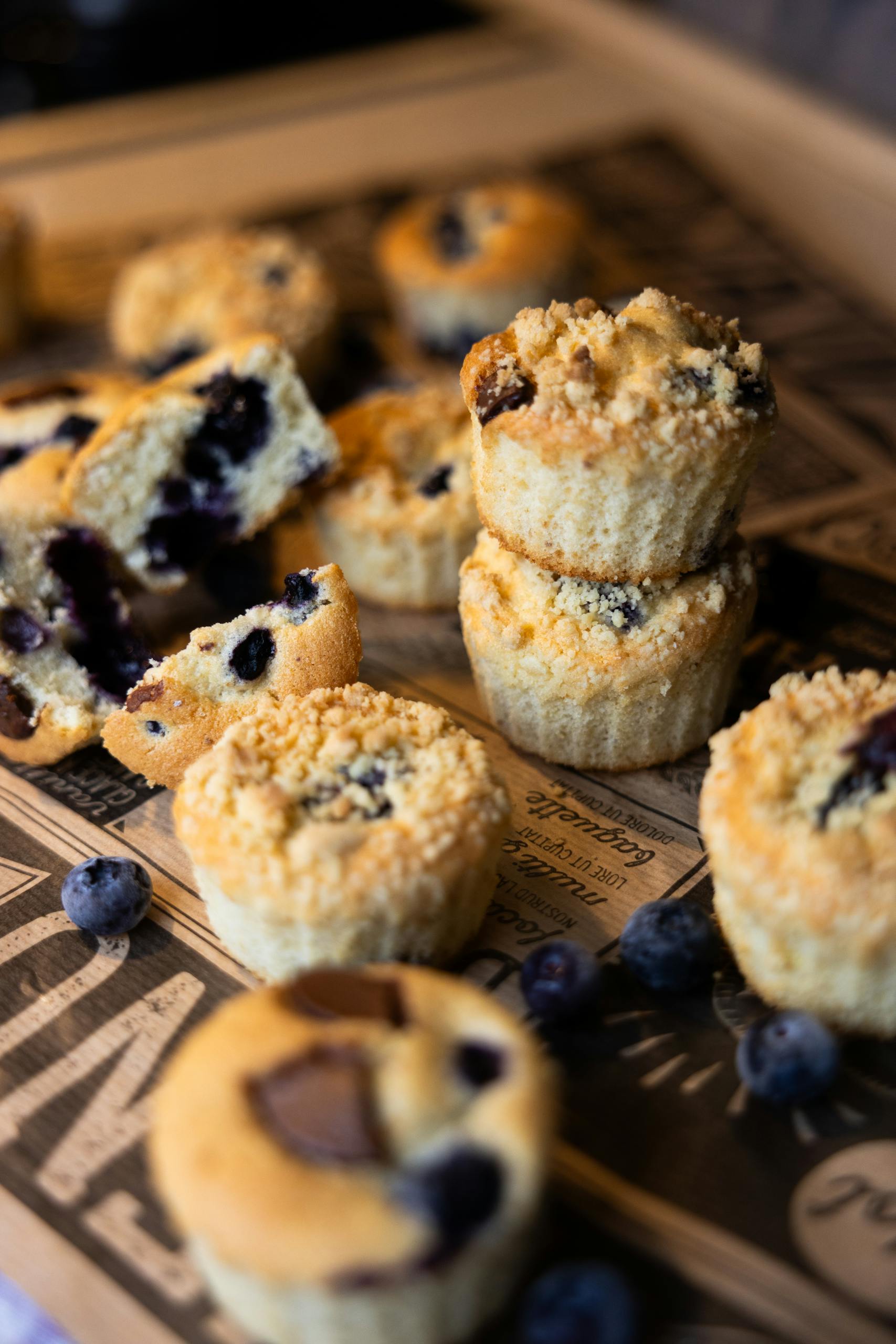 Freshly baked blueberry muffins with a crumbly topping on a rustic table.
