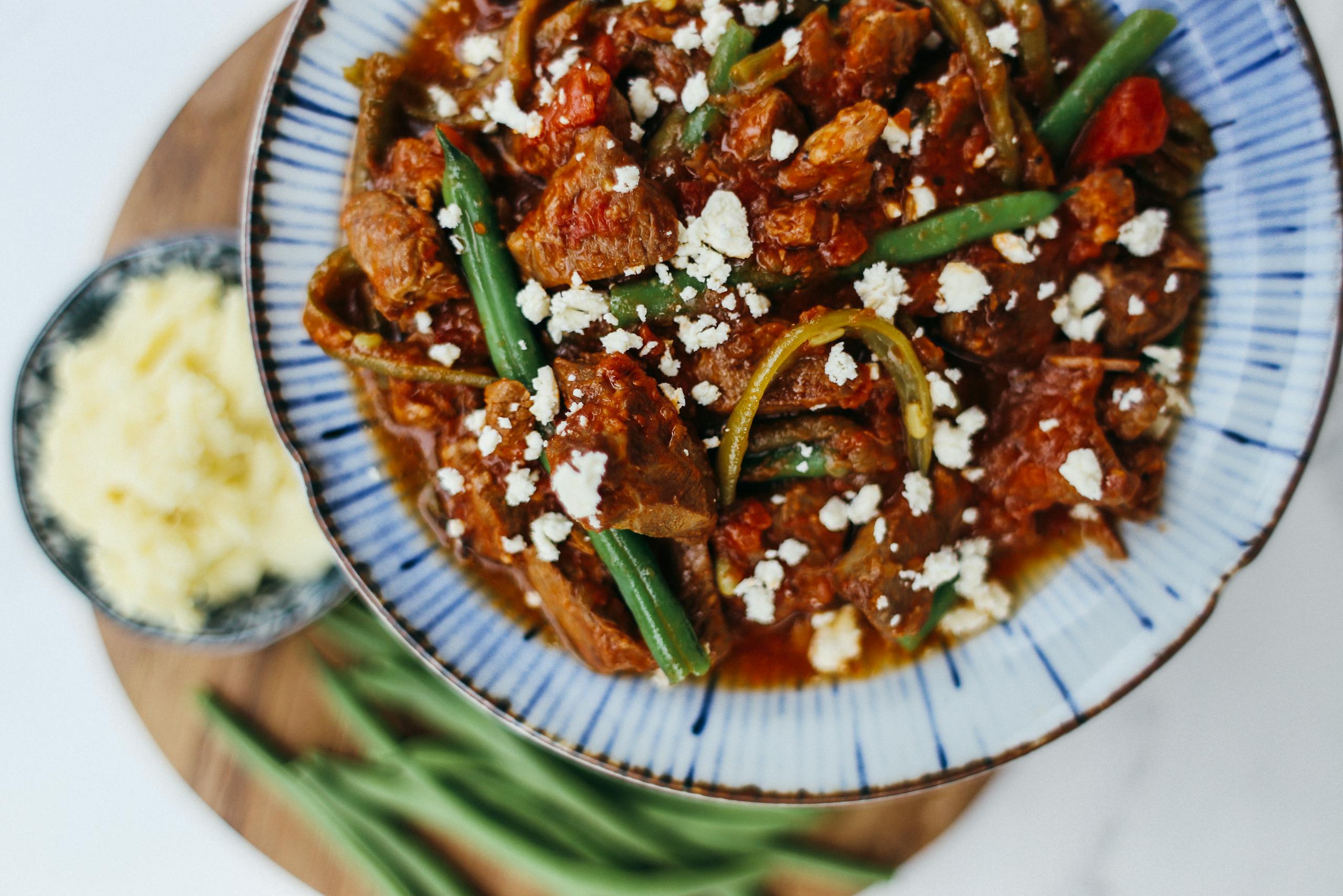 Savor a hearty lamb stew topped with green beans and cheese, perfect for a flavorful dinner.